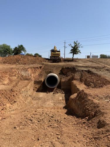 72" Storm drain peering out of a backfilled trench within Fancher Creek Detention Basin