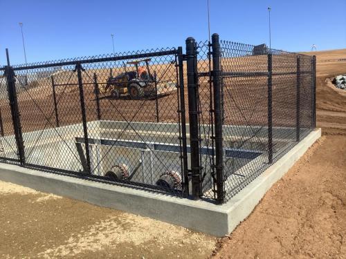 Completed pump intake structure with black vinyl coated chain link fencing around the perimeter
